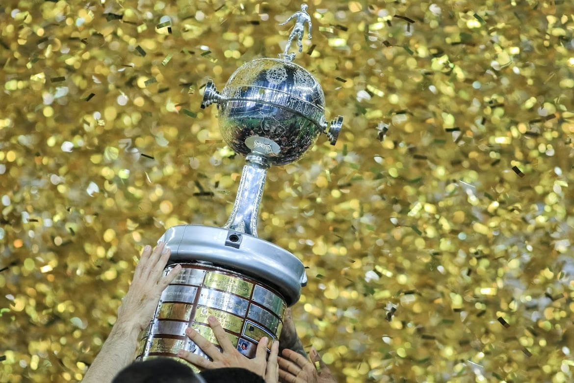 Taça da CONMEBOL Libertadores erguida durante a final do torneio, com confetes dourados ao fundo